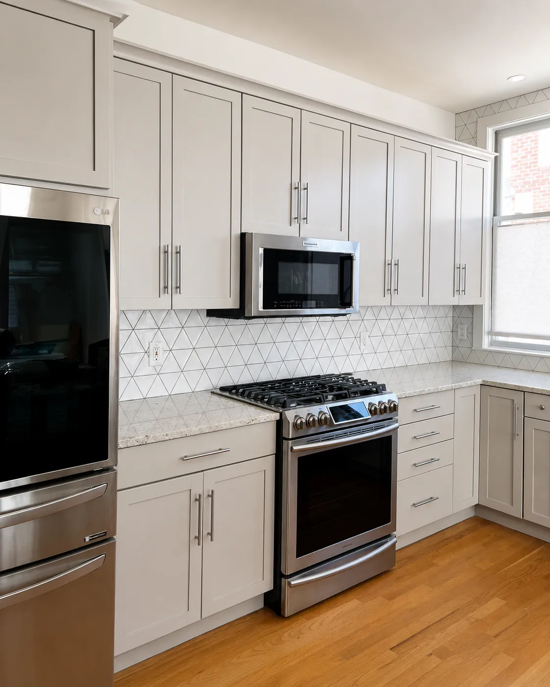 After - kitchen with refinished light cabinets and new tile backsplash by LMK Home Services